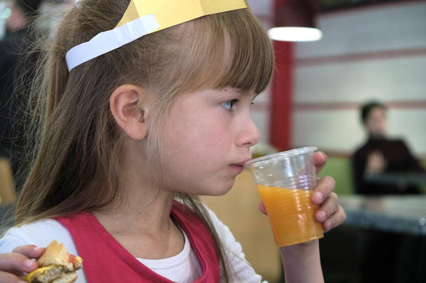 Κοντινό κομμάτι του χαριτωμένο παιδί κορίτσι πίνοντας χυμό πορτοκαλιού από πλαστικό c - Φωτογραφία, εικόνα