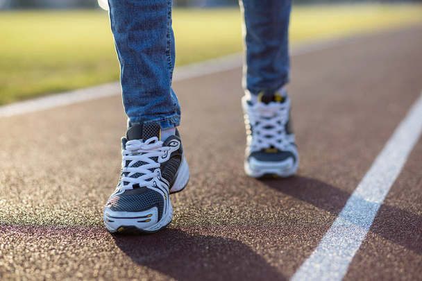 Close up of woman feet in sport sneakers and blue jeans on runni - Fotografie, Obrázek