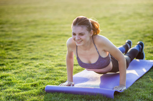 Молода спортивна жінка в спортивному одязі тренується в полі на сонці
 - Фото, зображення