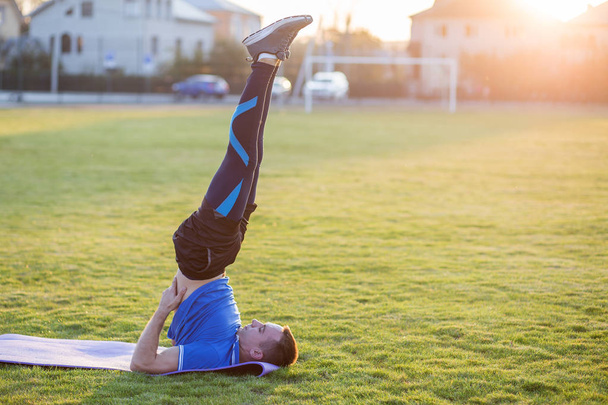 Mladý sportovní muž dělá cvičení v ranním poli venku. - Fotografie, Obrázek