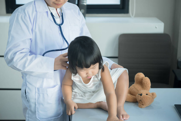 Азіатський лікар використовує стетоскоп, щоб перевірити його дихання і серце прекрасної дівчини, перевірити здоров'я дітей, жителів Таїланду - Фото, зображення