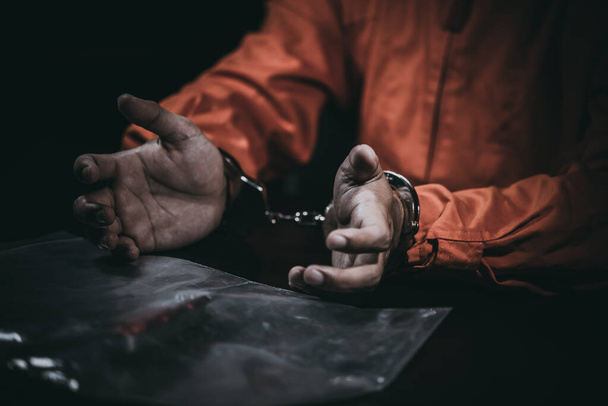 O suspeito usa panos de prisioneiro foi preso na investigação, entrevista para descobrir a verdade, o ladrão foi pego pela polícia vem para o quarto escuro, povo da Tailândia, faca na mão
 - Foto, Imagem