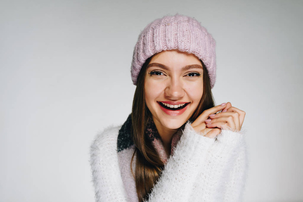 , lacht das Mädchen in flauschigem Pullover und Hut fröhlich. helles Atelier - Foto, Bild