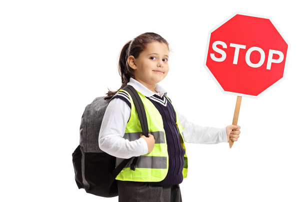 Schoolgirl with a stop sign and wearing a safety vest on white b - Фото, изображение