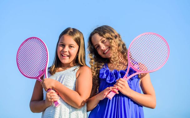 Taking a break. happy and cheerful. sport playing. summer outdoor games. play tennis. childhood happiness and sisterhood. small girls with tennis racquet. summer sport activity. energetic children - Foto, afbeelding