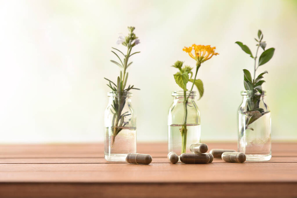 Natural herbal medicine capsules on wooden table with tree jars - Foto, Imagen