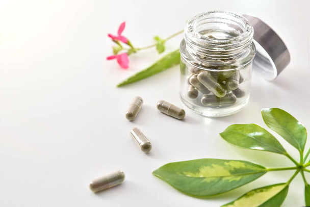 Natural medicine capsules in open glass jar on table elevated - Valokuva, kuva