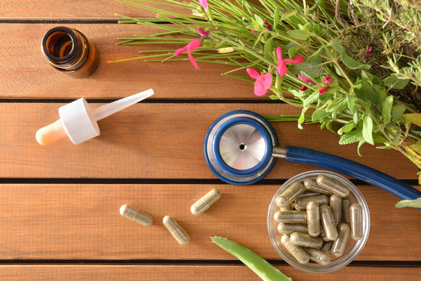 Luonnollinen lääketiede kapselit pöydällä housut ja stetoskooppi
 - Valokuva, kuva