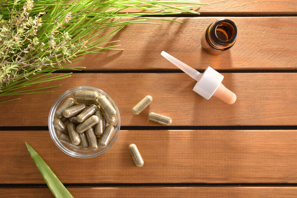 Cápsulas de medicina natural en la mesa con pantalones y top
 - Foto, imagen