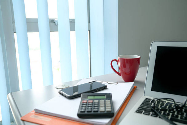 Vista de mesa de escritório ao lado de janelas com laptop. Foco em vermelho c
 - Foto, Imagem