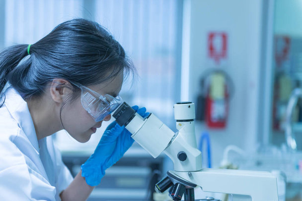 Giovane scienziato asiatico guardando attraverso un microscopio in un laboratorio.Thailandia persone che fanno qualche ricerca
. - Foto, immagini