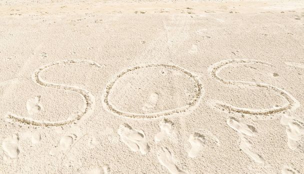 Kirjoita SOS hiekalla rannalla lähellä merta - Valokuva, kuva