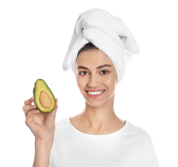 Happy young woman with towel holding avocado on white background. Organic face mask - 写真・画像
