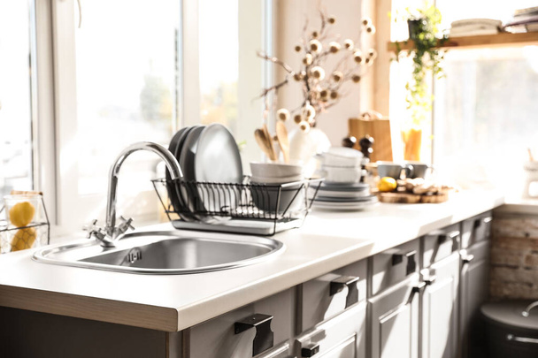 Stylish kitchen with sink and clean dishware - Foto, afbeelding