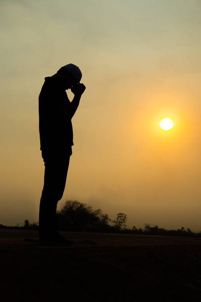 Silhouette Fiatal ázsiai muszlim férfi imádkozik naplemente, Ramadan fesztivál koncepció - Fotó, kép