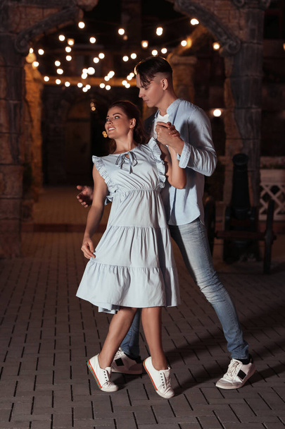 Όμορφο νεαρό ζευγάρι που εξασκείται χορευτικές κινήσεις σε εξωτερικούς χώρους το βράδυ - Φωτογραφία, εικόνα
