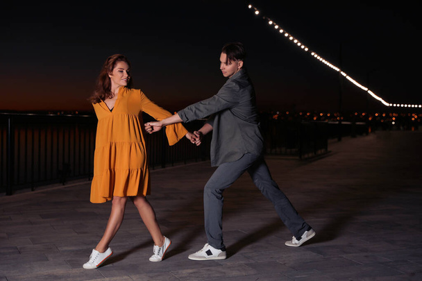 Beau jeune couple pratiquant des mouvements de danse en soirée en plein air
 - Photo, image