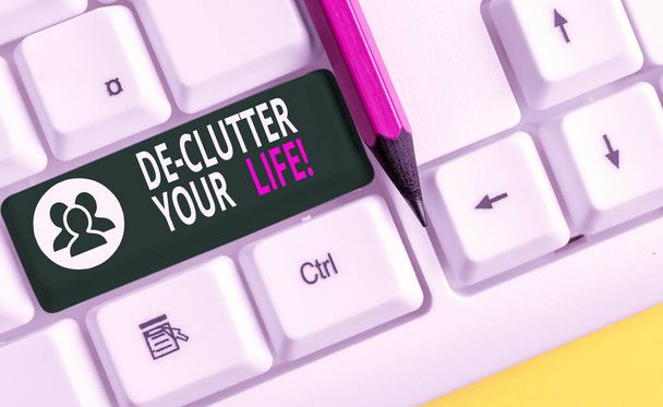 Conceptual hand writing showing De Clutter Your Life. Business photo text remove unnecessary items from untidy or overcrowded places White pc keyboard with note paper above the white background. - Photo, Image