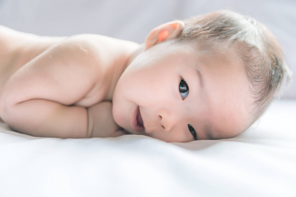 süßes asiatisches Baby liegt auf dem Bett aus dem vorderen Winkel - Foto, Bild