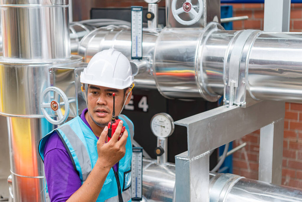 asiatischer Ingenieur mit Brille, der im Heizungsraum arbeitet und technische Daten von Heizungsanlagen überprüft, Thailänder - Foto, Bild