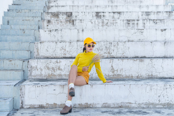 Portrait of beautiful asian woman in yellow cloths,Hipsters girl wear yellow hat on stair for take a picture,Thailand people in yellow tone style - Foto, immagini
