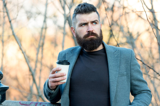 Hot drink on autumn day outdoors. Morning inspiration. Thoughtful man drink take away coffee. Coffee aesthetics. Mature hipster with beard with coffee cup. Energy charge. Guy enjoying every sip - Foto, Imagem