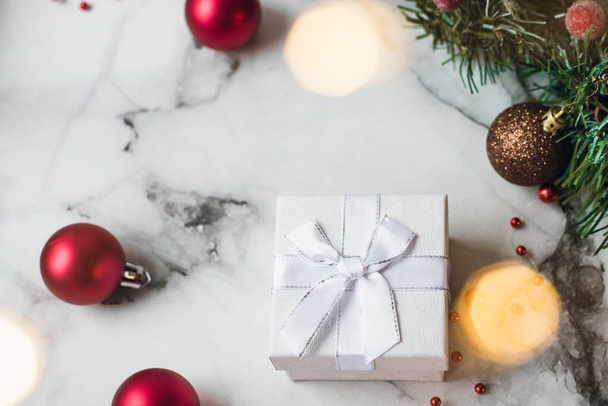 Stříbrný dárek na mramorovém pozadí s červenými vánoční koule a vánoční věnec. Koncept Nového roku a Vánoc, světlé žluté věnce a dárky na dovolenou - Fotografie, Obrázek
