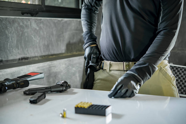 Asian male wearing black leather gloves with gun in hand,loading bullets to gun - Foto, afbeelding