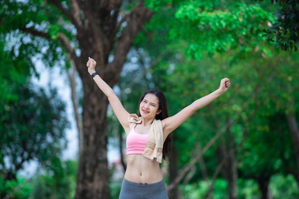 Asian sporty woman stretching arms breathing fresh air in the park,Thailand people exercise concept - Valokuva, kuva