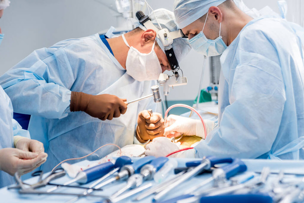 Cirugía de columna. Grupo de cirujanos en quirófano con equipo quirúrgico. Laminectomía. Formación médica moderna
 - Foto, Imagen
