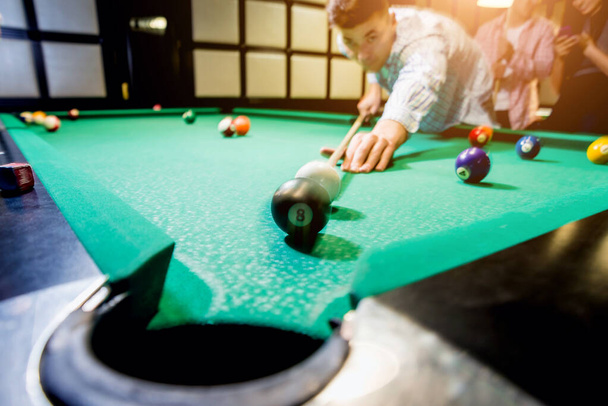 Young man trying to hit the ball in billiard. Pool background - 写真・画像