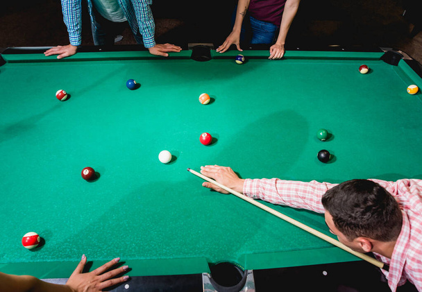 Young man trying to hit the ball in billiard. Pool background - Foto, afbeelding