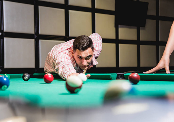 Young man trying to hit the ball in billiard. Pool background - Foto, immagini
