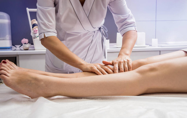 Hermosa mujer joven disfrutando de masajes en las piernas en el salón de spa. Concepto de cosmetología
 - Foto, imagen