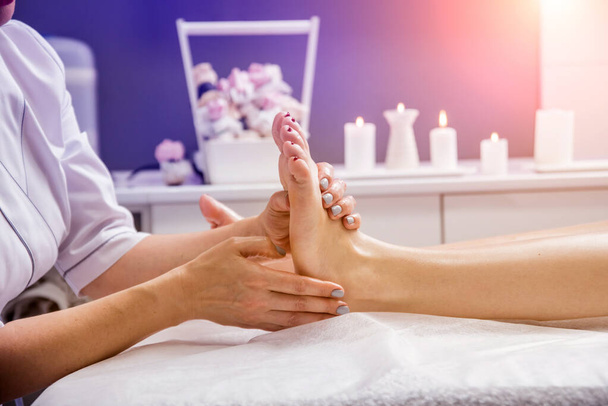Beautiful young woman enjoying foot massage in spa salon. Cosmetology concept - Foto, afbeelding