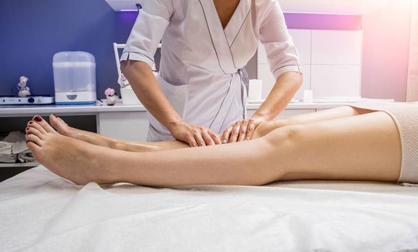 Beautiful young woman enjoying legs massage in spa salon. Cosmetology concept - Fotó, kép