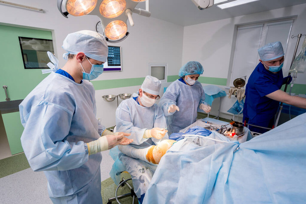 Cirugía de artroscopio. Cirujanos ortopédicos en equipo en quirófano con modernas herramientas artroscópicas. Cirugía de rodilla. Fondo hospitalario - Foto, Imagen