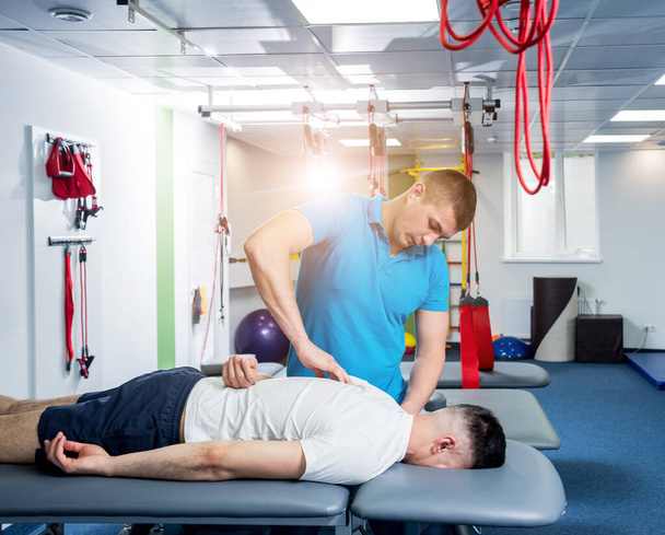 Rehabilitation therapy. Physiotherapist working with young male patient in the rehabilitation center. Treatment pain in spine - Valokuva, kuva