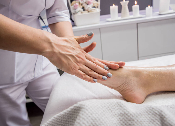 Beautiful young woman enjoying foot massage in spa salon. Cosmetology concept - Foto, Imagen