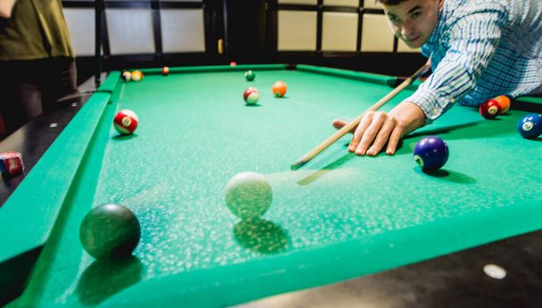 Young man trying to hit the ball in billiard. Pool background - Foto, imagen