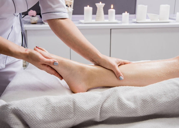 Beautiful young woman enjoying foot massage in spa salon. Cosmetology concept - Photo, image