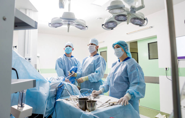 Arthroscope surgery. Orthopedic surgeons in teamwork in the operating room with modern arthroscopic tools. Knee surgery. Hospital background - Foto, imagen