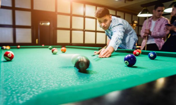 Young man trying to hit the ball in billiard. Pool background - Foto, Imagem