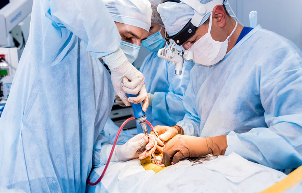 Cirurgia da coluna. Grupo de cirurgiões em centro cirúrgico com equipamento cirúrgico. Laminectomia. Contexto médico moderno
 - Foto, Imagem