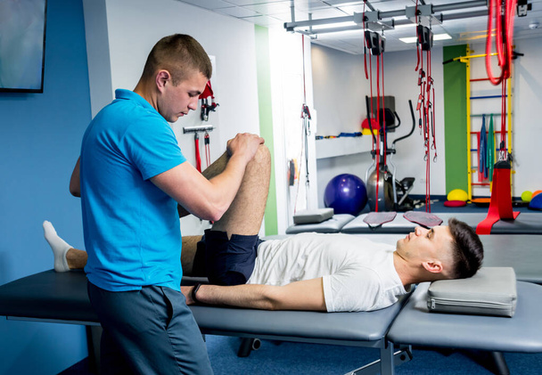 Rehabilitationstherapie. Physiotherapeut arbeitet mit jungen männlichen Patienten im Reha-Zentrum - Foto, Bild