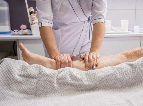 Beautiful young woman enjoying legs massage in spa salon. Cosmetology concept - Photo, image