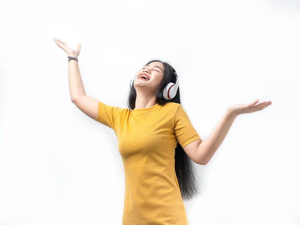 Happy Asian woman in yellow dress using headphone with pink back - Foto, immagini