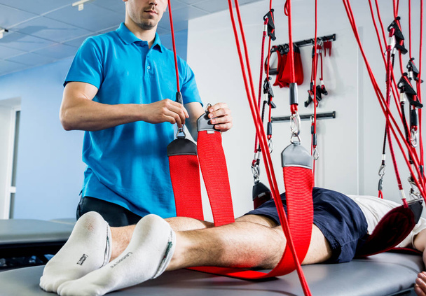 Physiotherapy. Suspension training therapy. Young man doing fitness traction therapy with suspension-based exercise training system - Foto, Bild