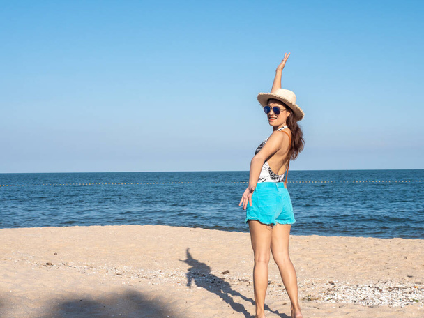 Happy Asian woman enjoying on the beach with straw hat in sunny  - Fotó, kép