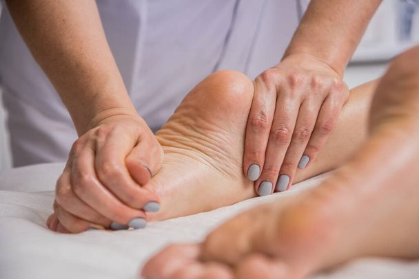 Beautiful young woman enjoying foot massage in spa salon. Cosmetology concept - Foto, imagen